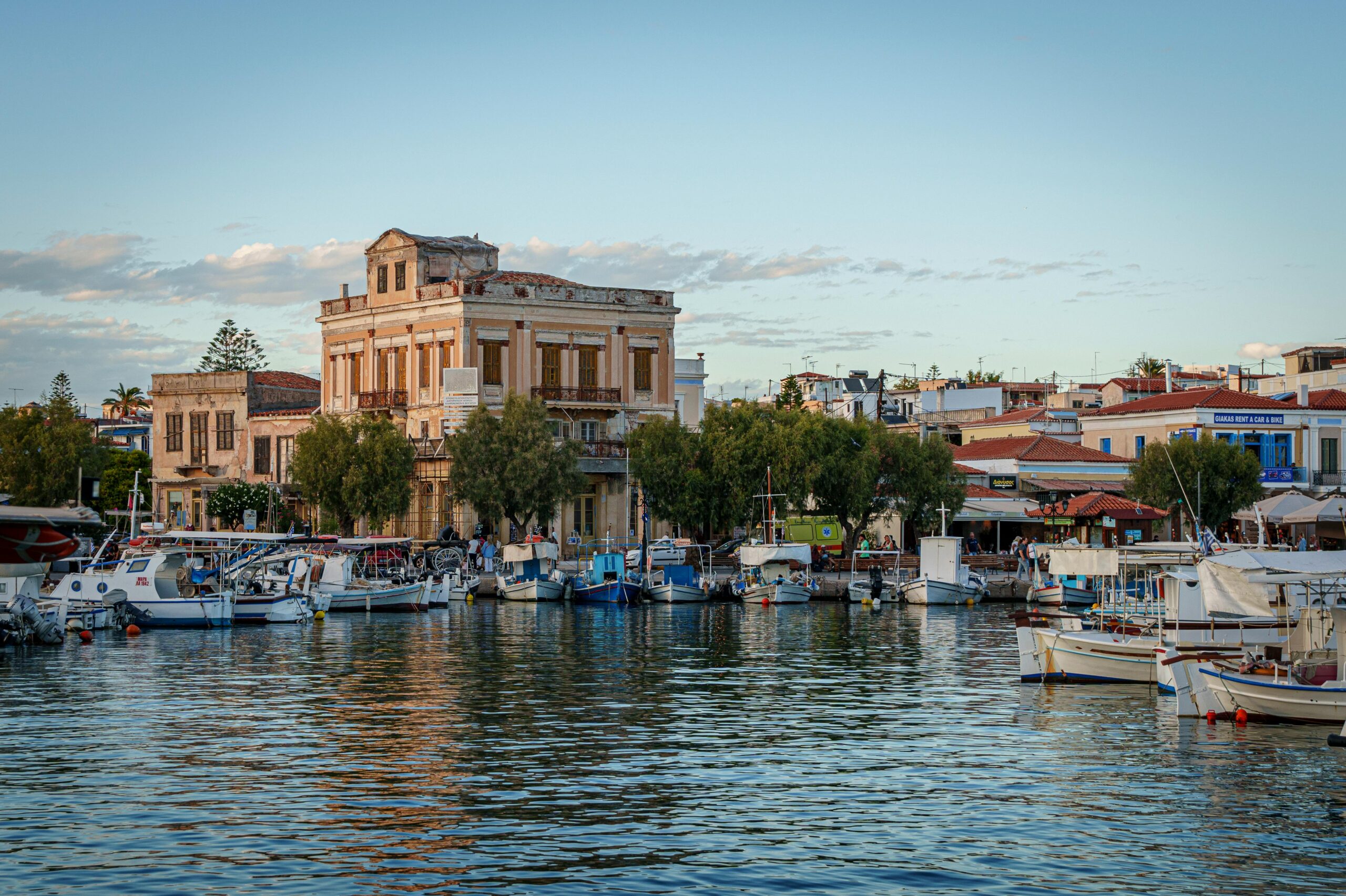 Beautiful marina scene with boats and historic architecture in Aegina, Greece.